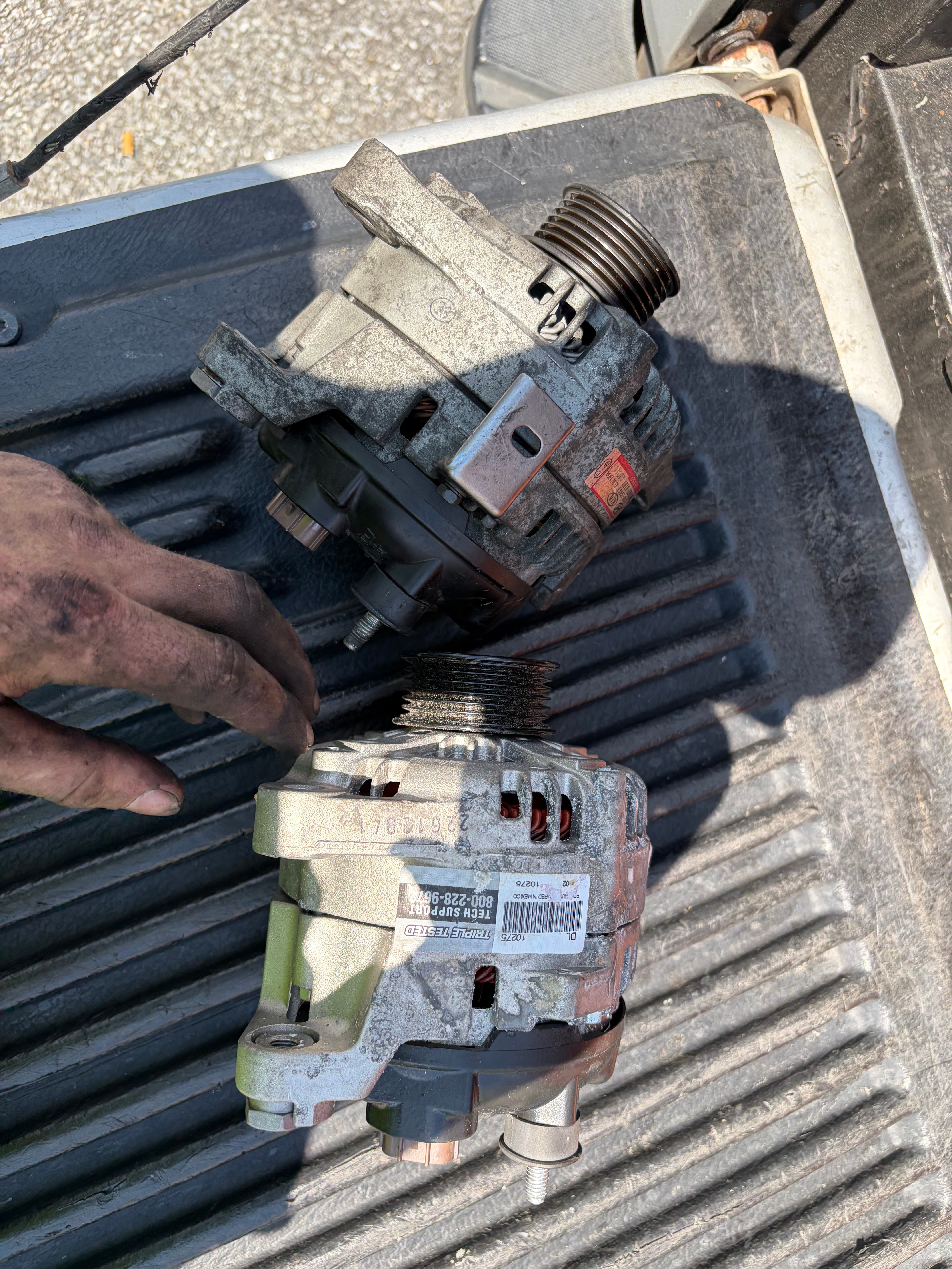 Comparing the failed alternator with the replacement unit.